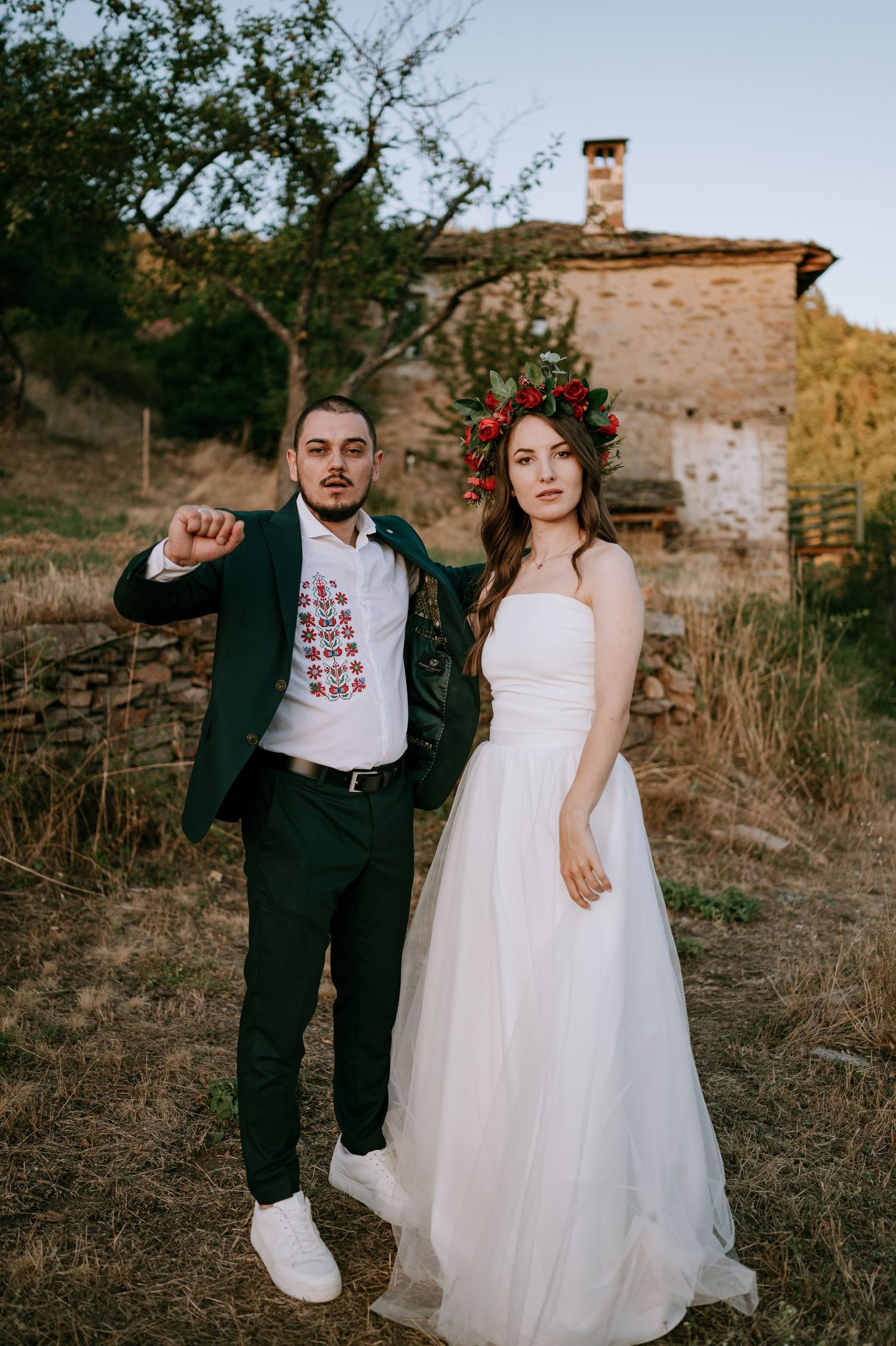 Wedding couple posing in rustic outdoor setting with old building in background.