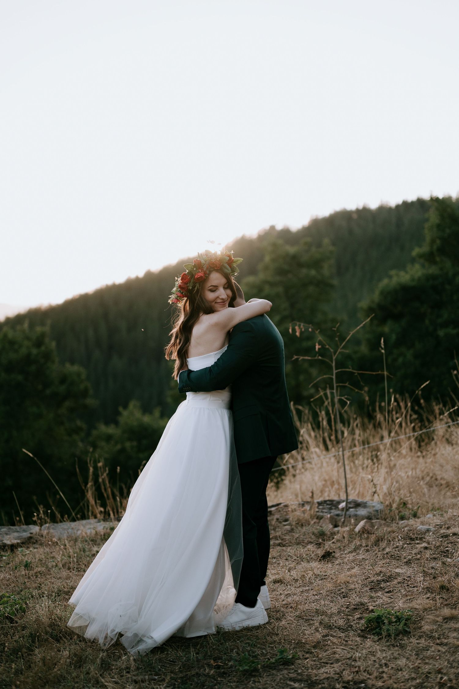 Newlyweds share a romantic dance in an outdoor setting with mountains in the background.