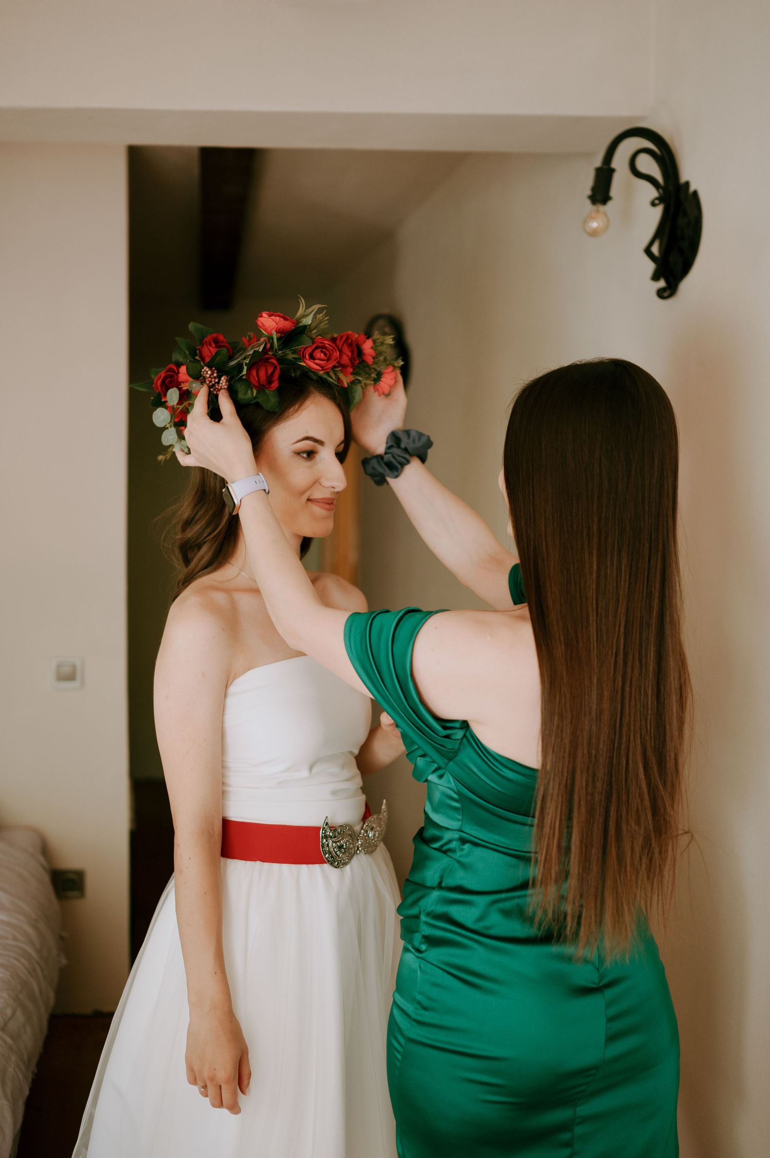 Two people in contrasting white and green dresses preparing for a special event.