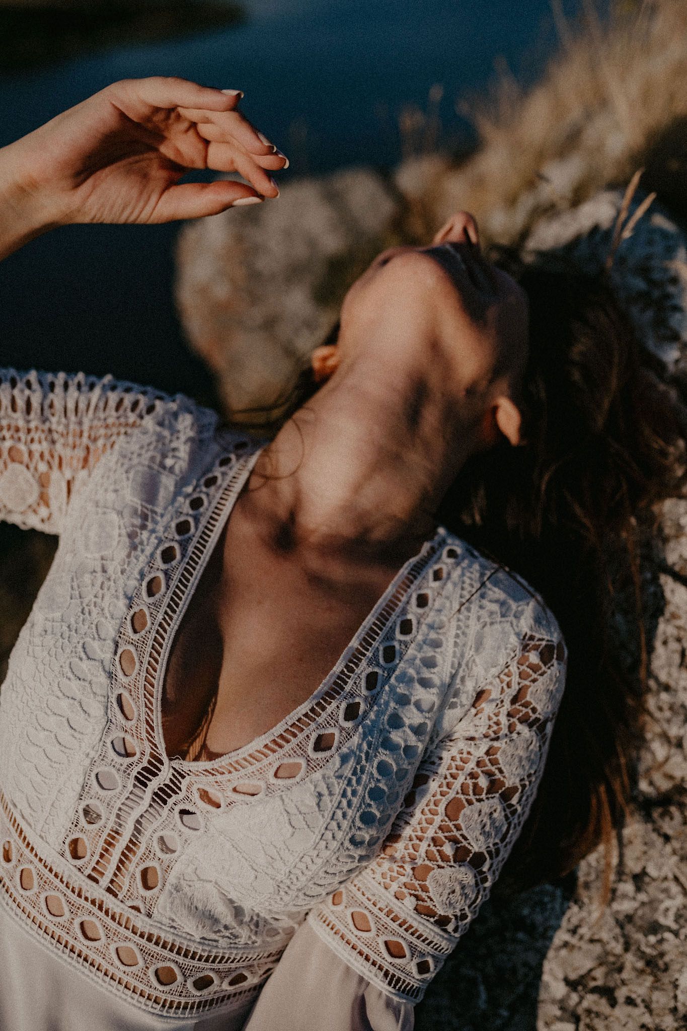 Detail shot of white lace dress pattern in natural sunlight against rocky background.