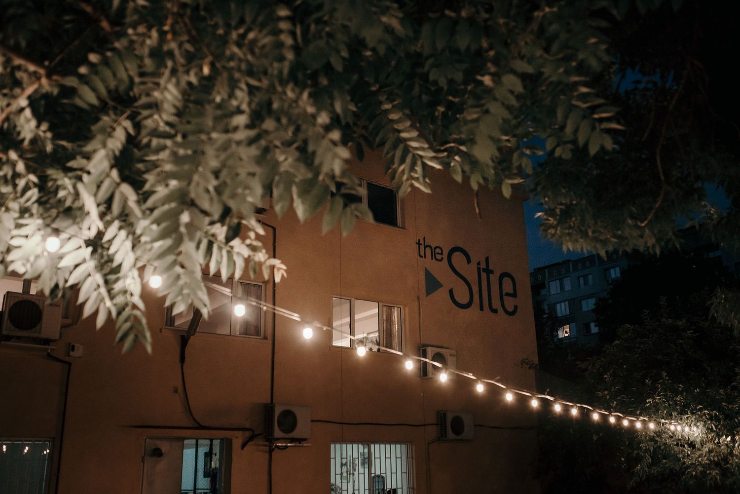 String lights illuminate a dark outdoor patio space creating a warm, ambient atmosphere.