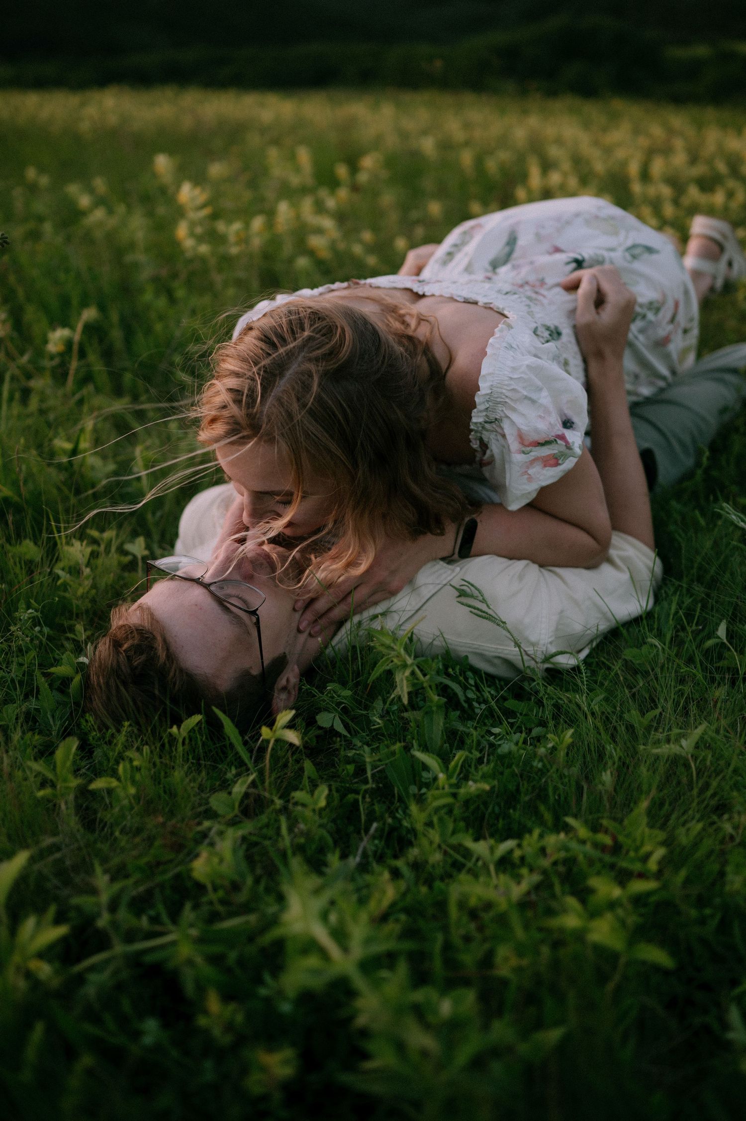 A dreamy portrait of someone lying in a lush green field at sunset.