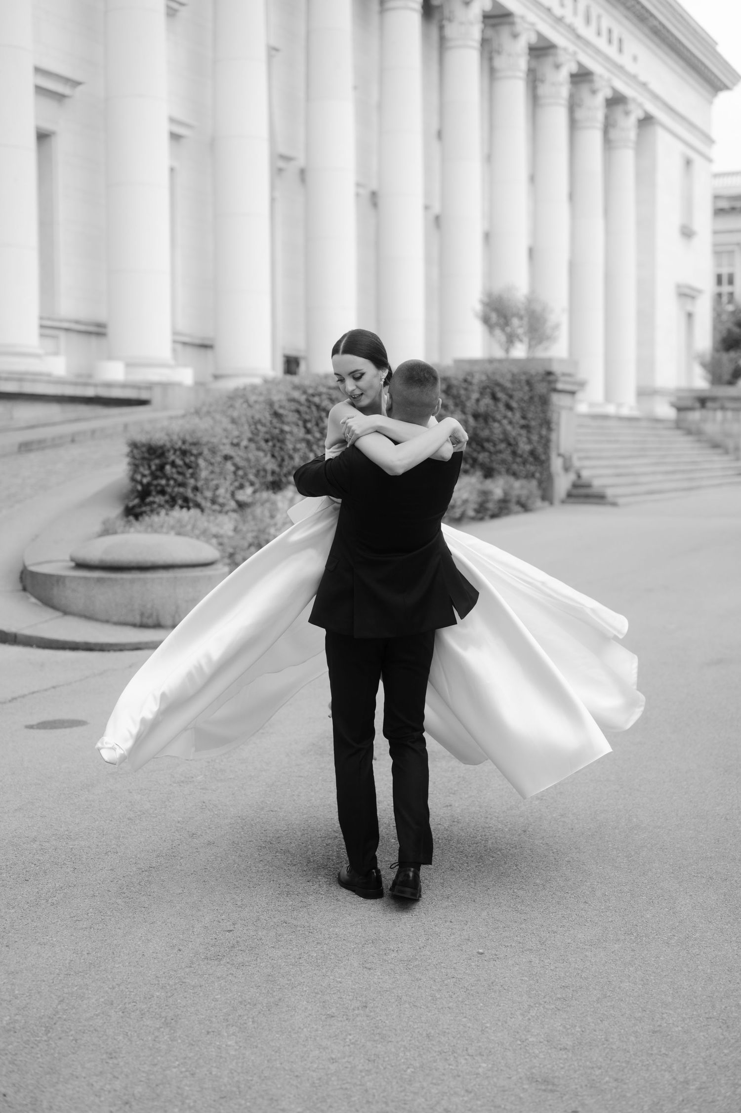A figure in black clothing spins gracefully with flowing white fabric creating an ethereal motion effect in a classical setting.