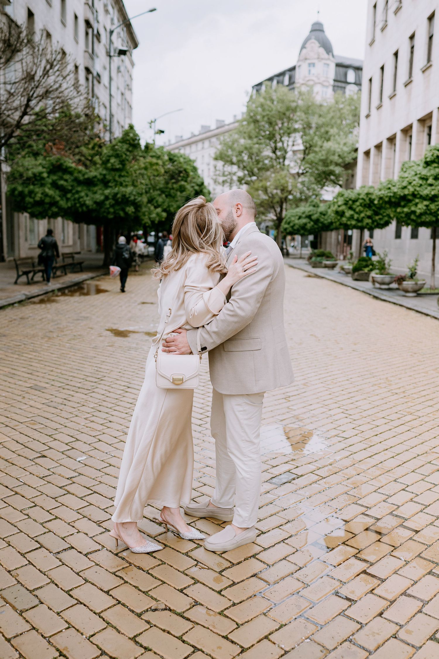 Romantic dance sequence on cobblestone street with couple in cream-colored outfits.