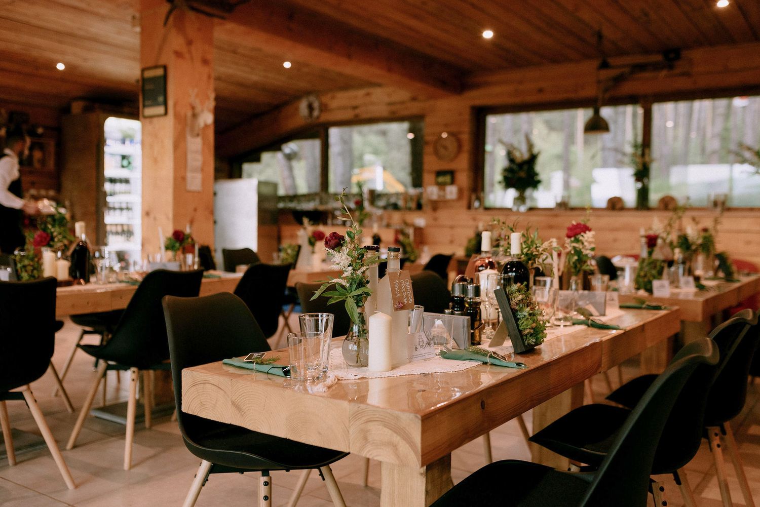 Rustic wooden barn venue interior with elegant table settings and warm lighting for a wedding reception.
