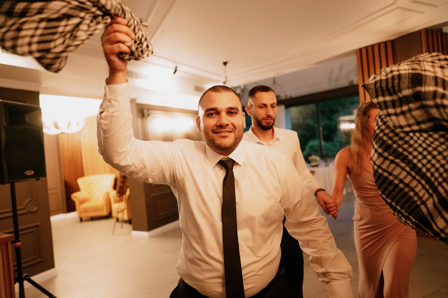 Wedding guests dancing and celebrating on the dance floor during reception.