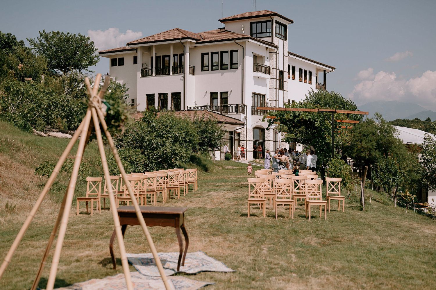 Panoramic view of a rustic wedding venue with wooden chairs set up on rolling hills.