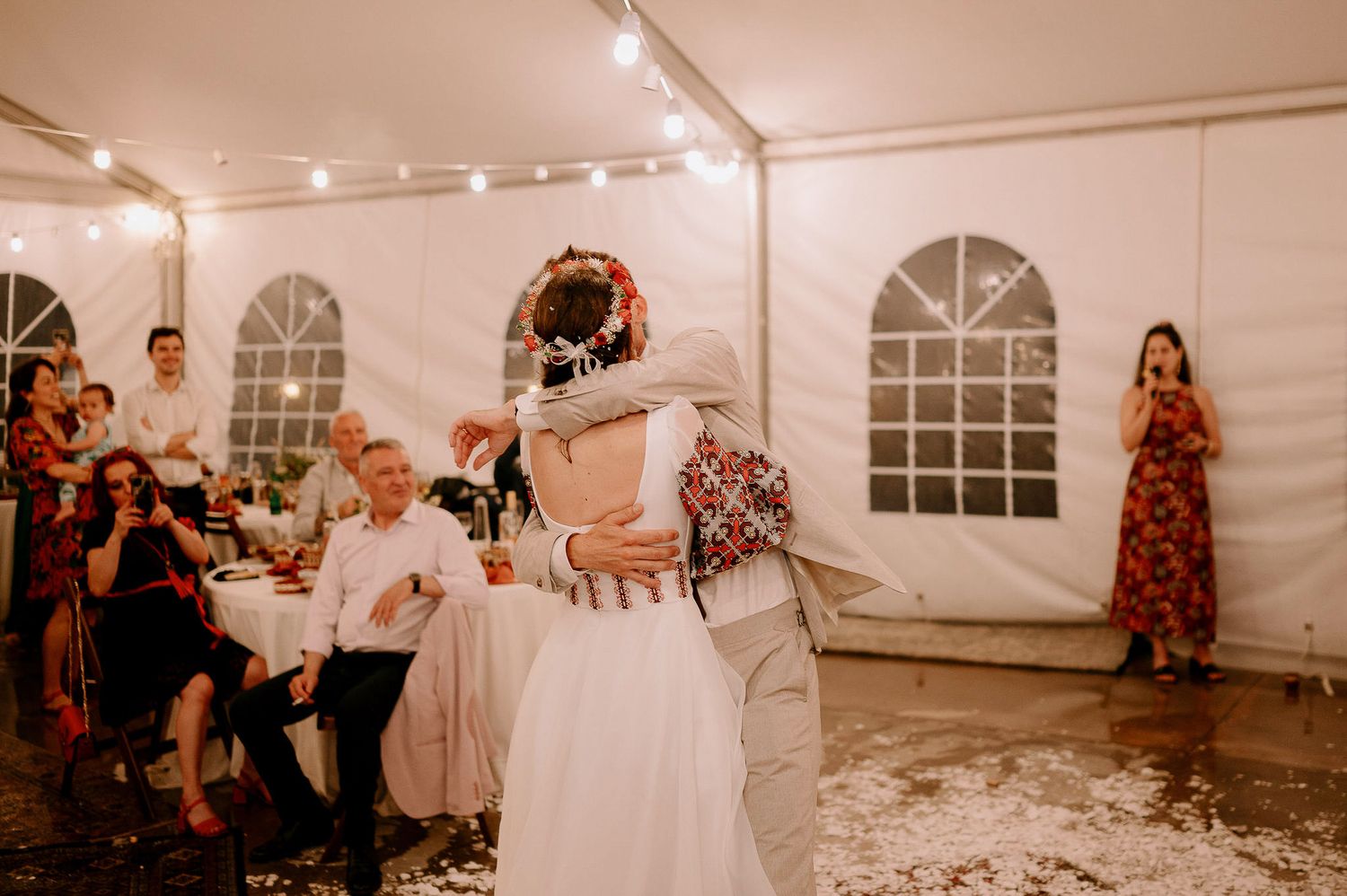 Wedding celebration inside a white tent venue with string lights creating a warm ambiance.