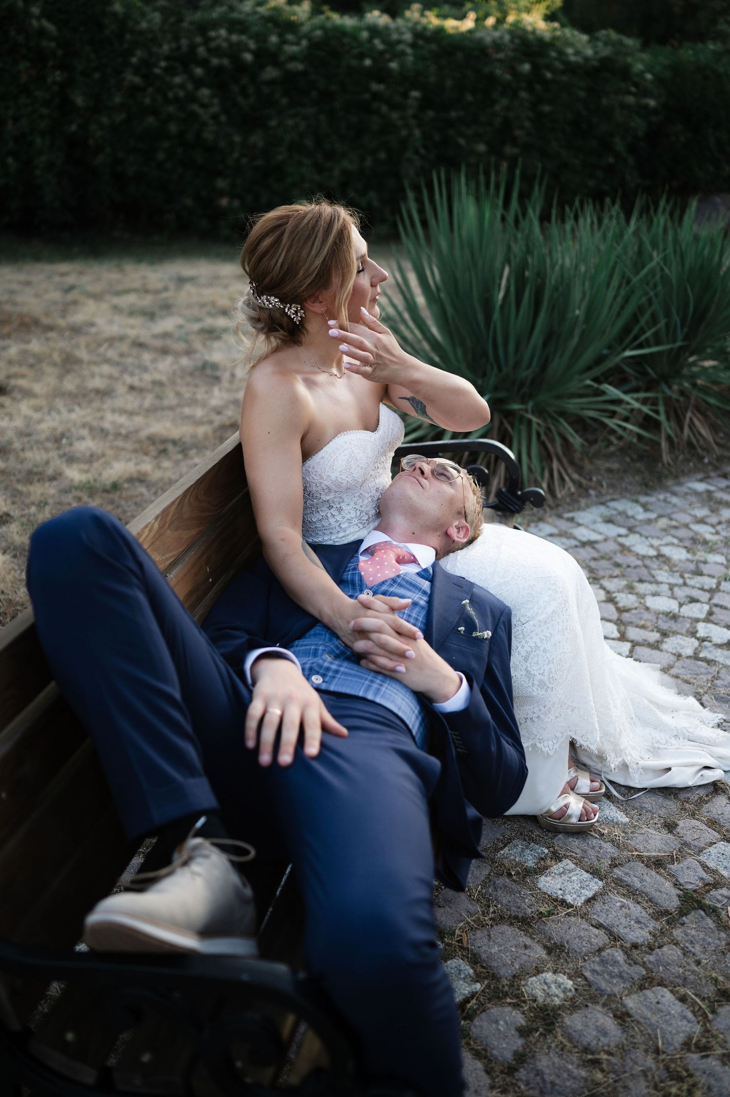 Intimate wedding portraits captured on a park bench with natural garden scenery.