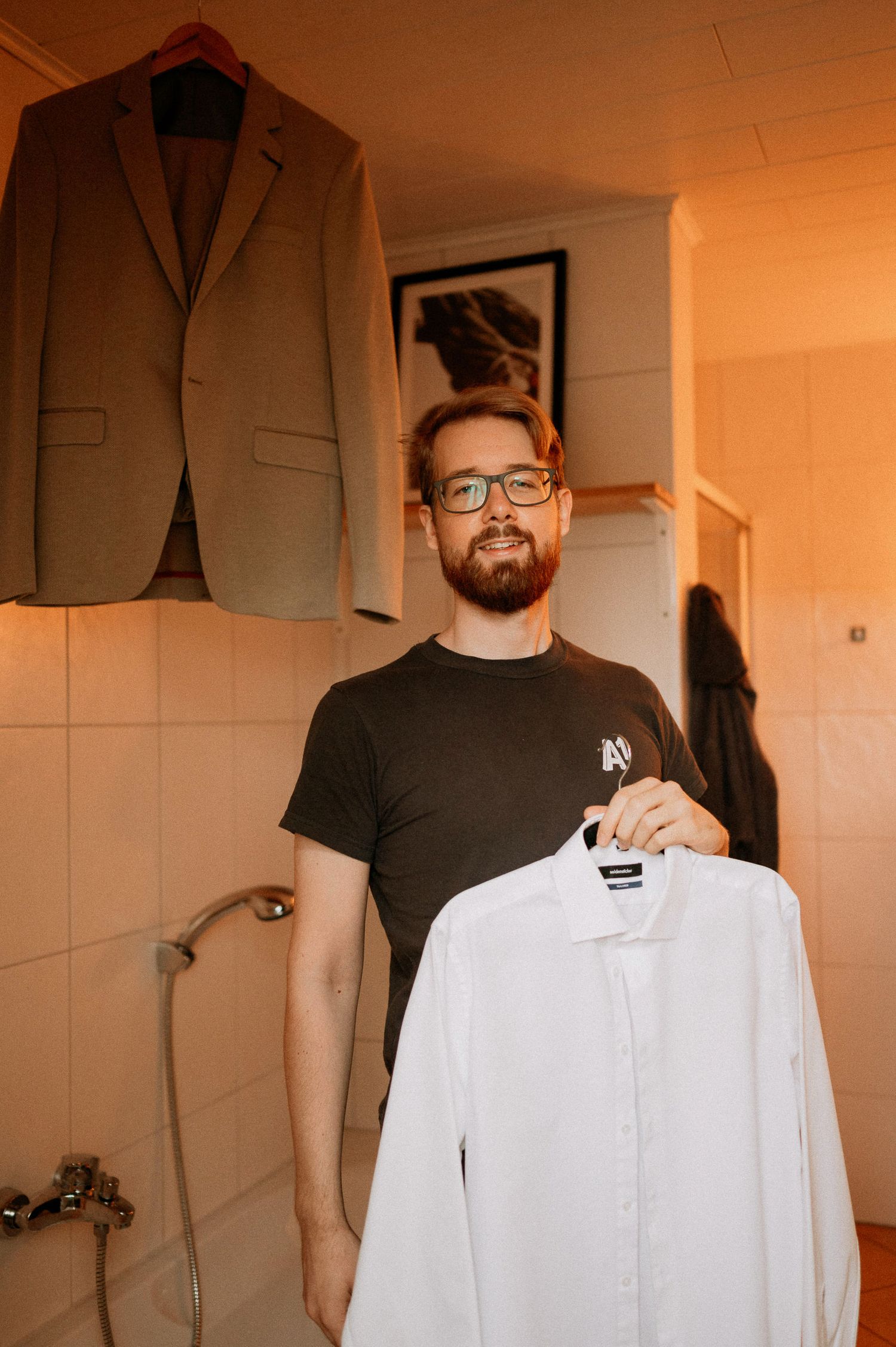 Wedding attire displayed on hangers with a tan suit jacket and white shirt visible.