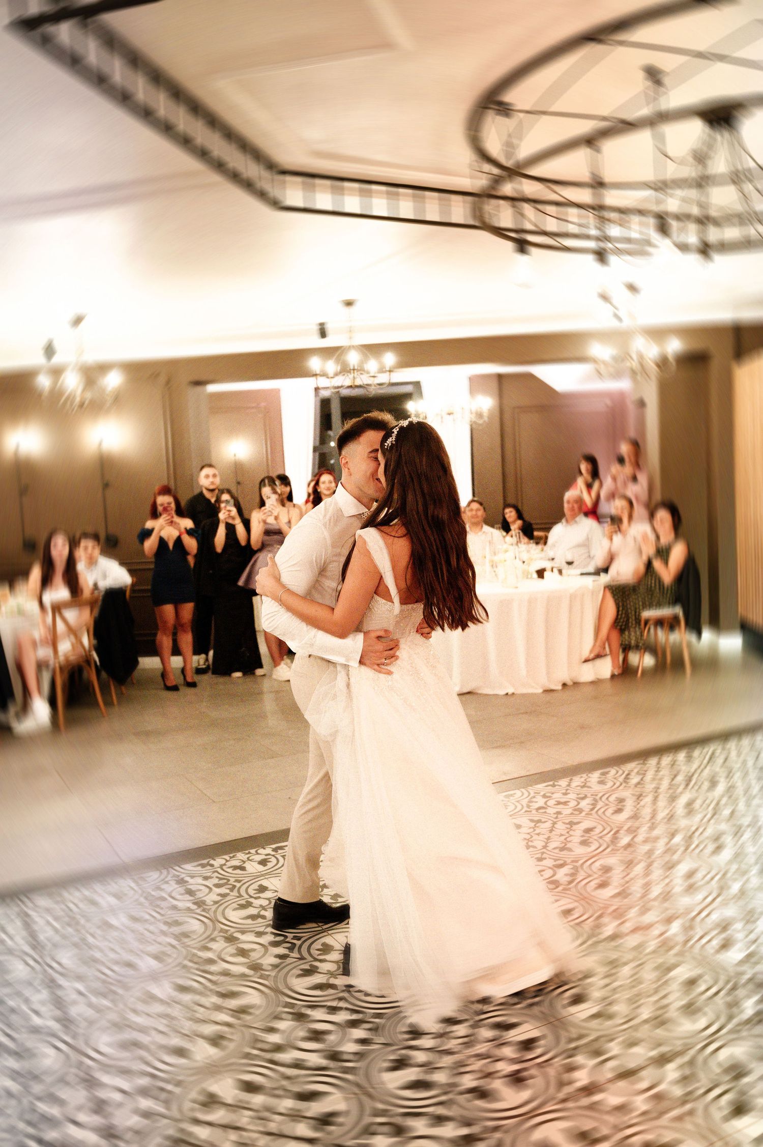 Couple dancing gracefully across a patterned ballroom floor at a wedding reception.