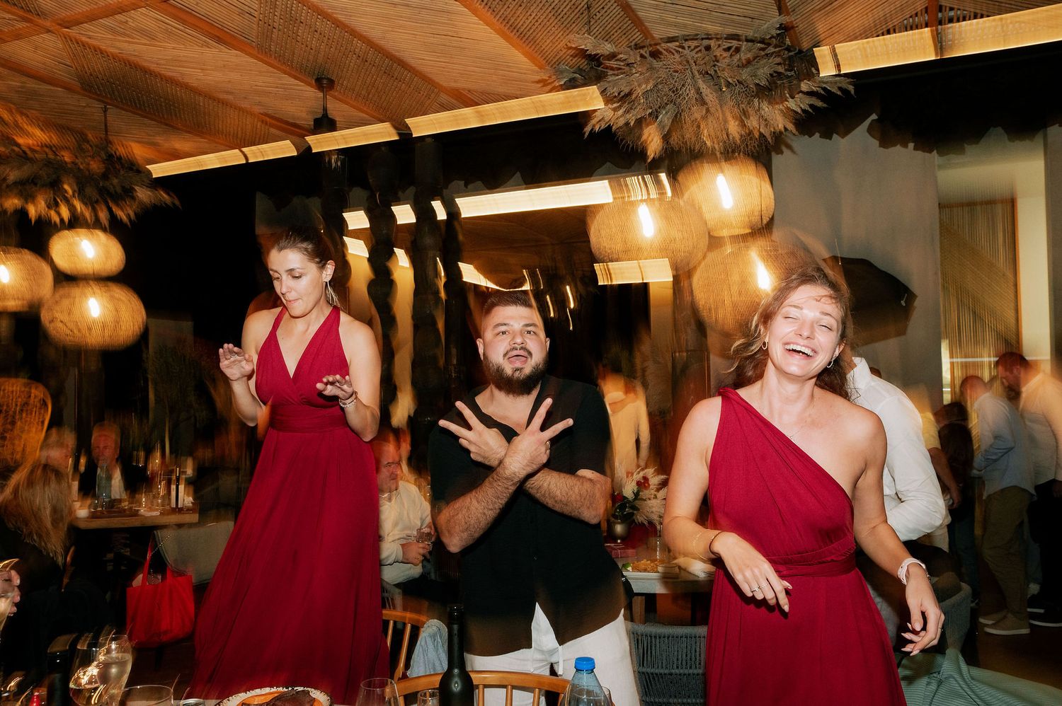 People dancing and celebrating at a dimly lit indoor reception venue.