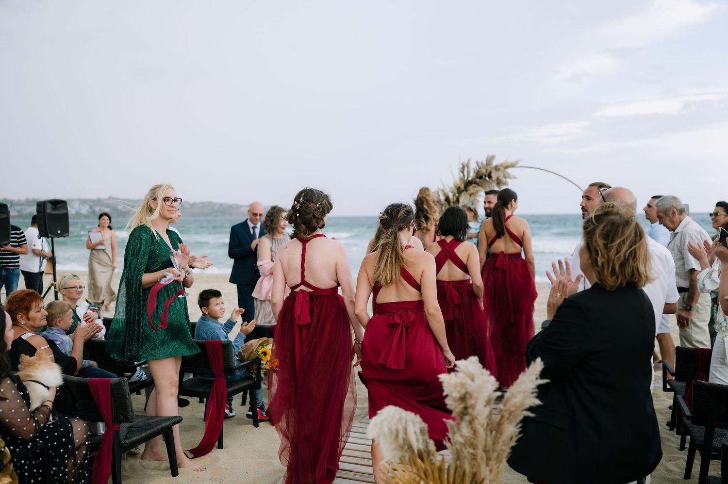 Wedding guests and bridal party gathered on beach for outdoor ceremony.