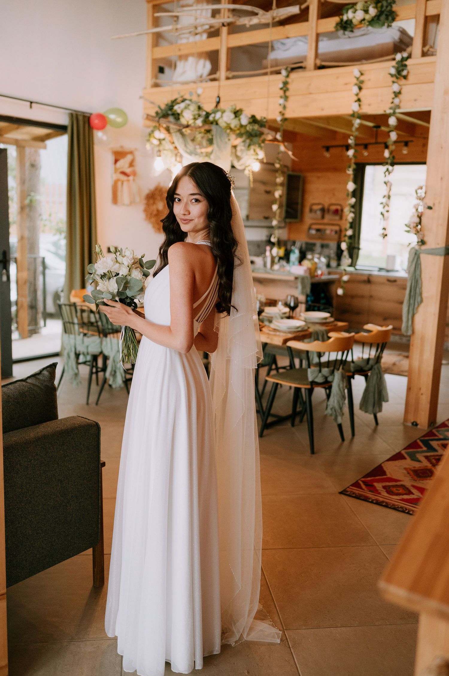 A rustic wedding reception space with wooden details and hanging greenery creates a warm atmosphere.