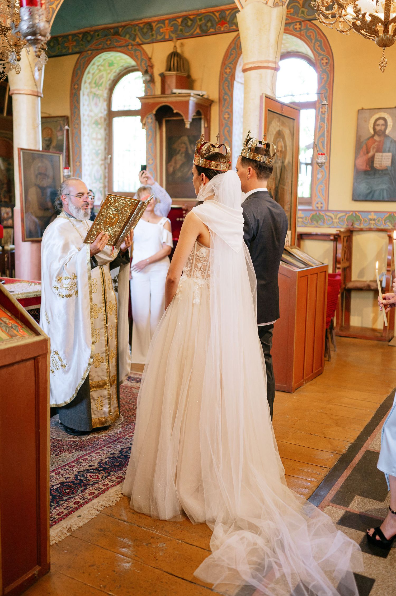 Orthodox wedding ceremony in a traditional church with ornate decorations and religious icons on display.
