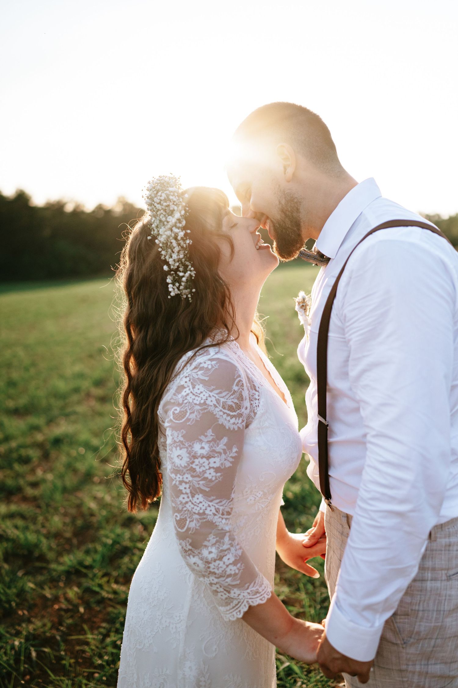 Romantic sunset wedding photoshoot showing couple in white attire with delicate lace details and baby's breath flowers.