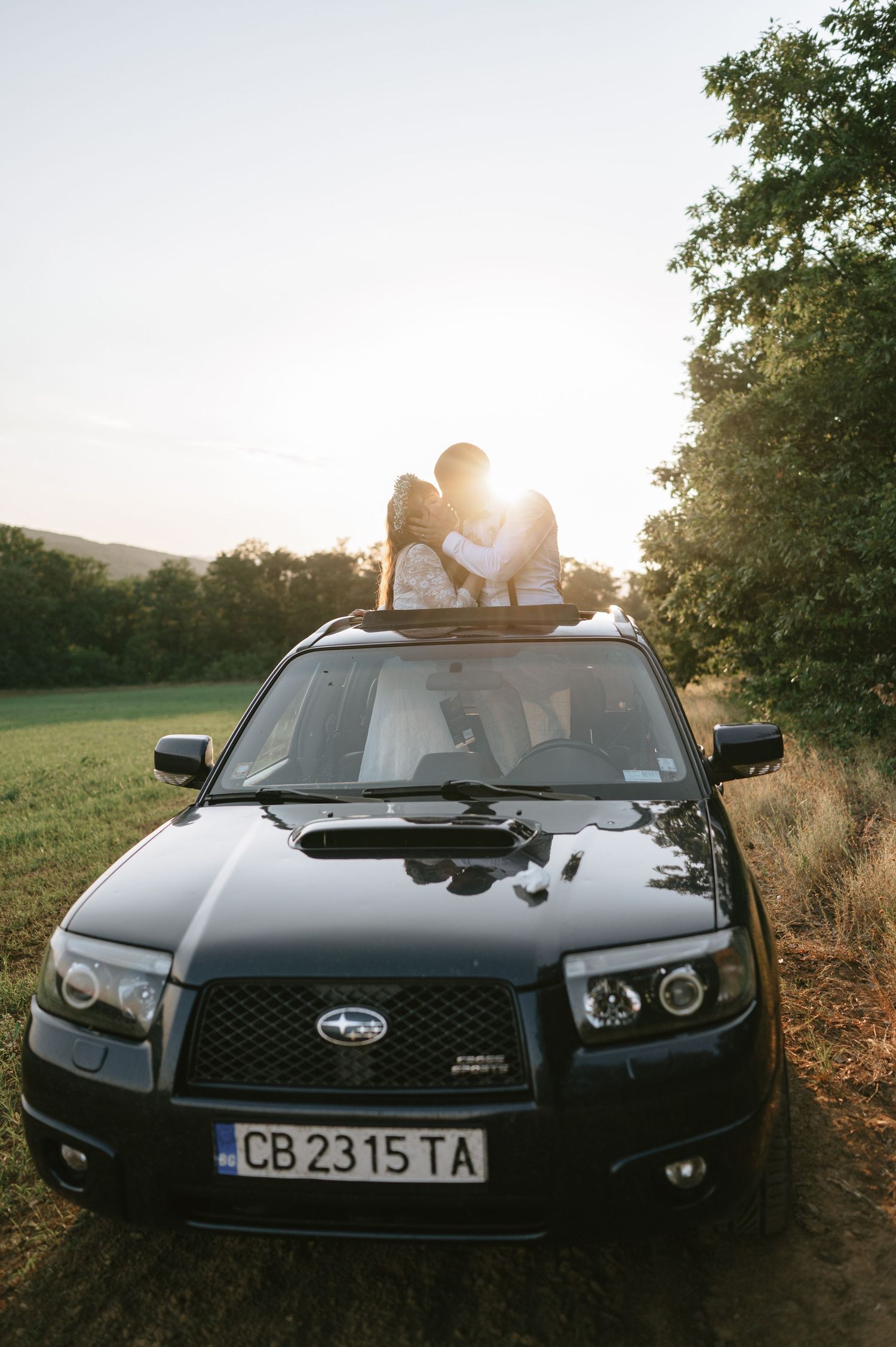 A black Subaru car photographed at sunset with romantic lighting.