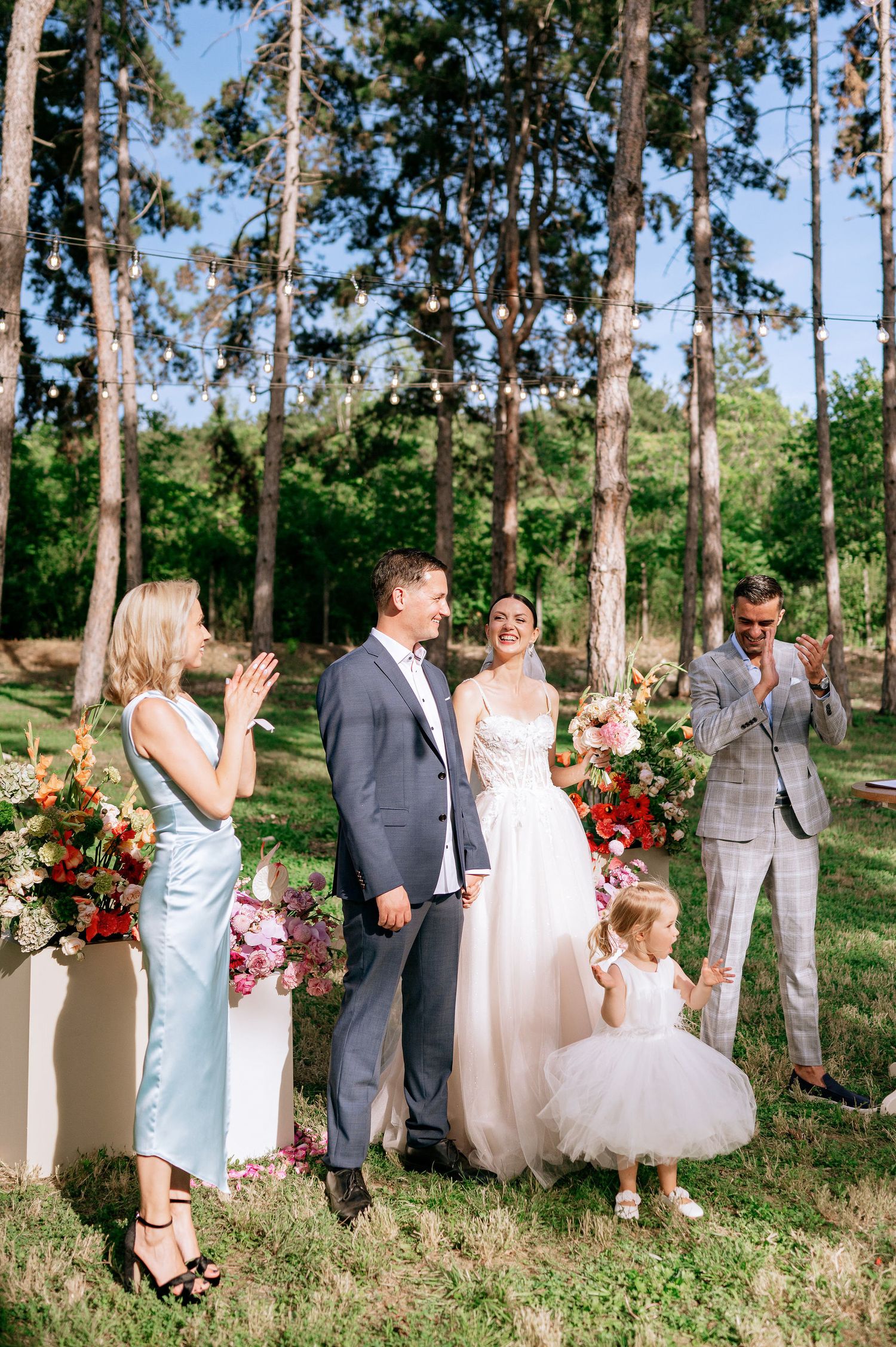 Wedding celebration with guests and wedding party in a natural forest setting.