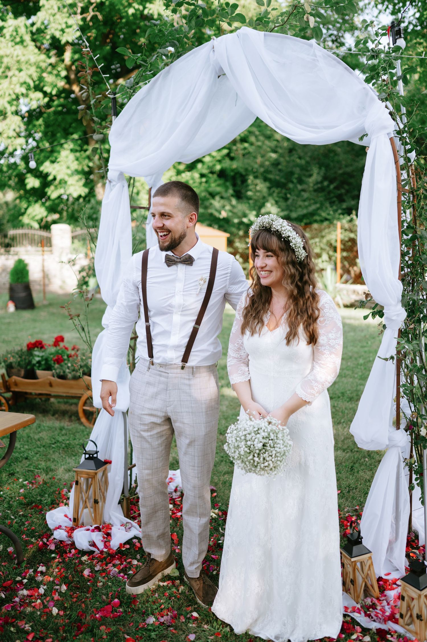 An intimate garden wedding scene with white drapery and floral decorations.