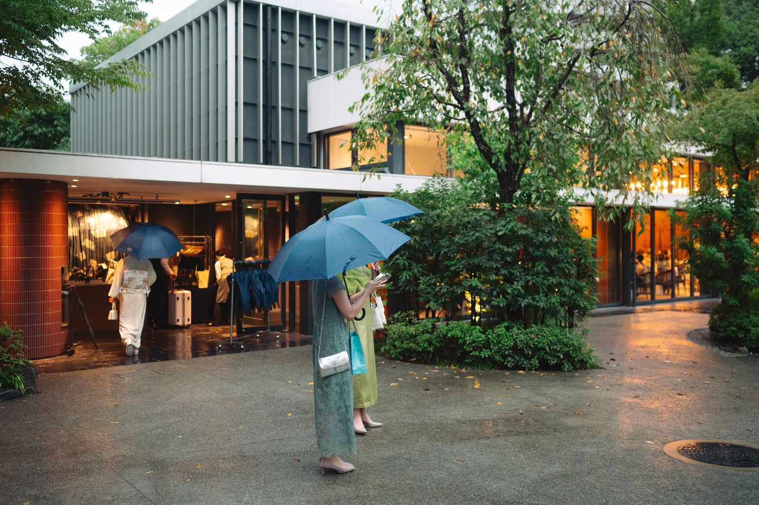 Modern building exterior with curved walkway and landscaping at dusk.