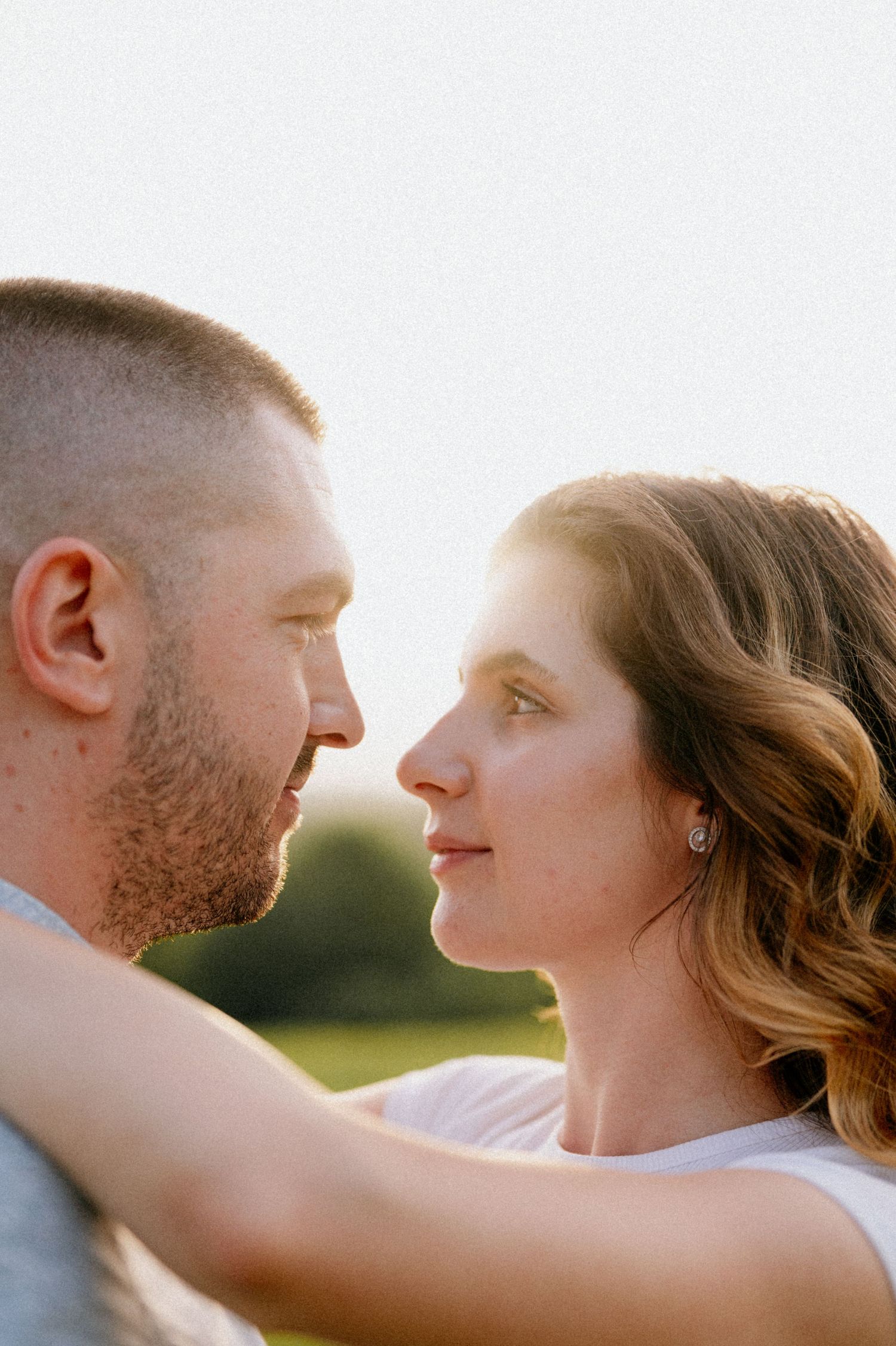 Intimate portrait of couple gazing at each other in warm sunlight.