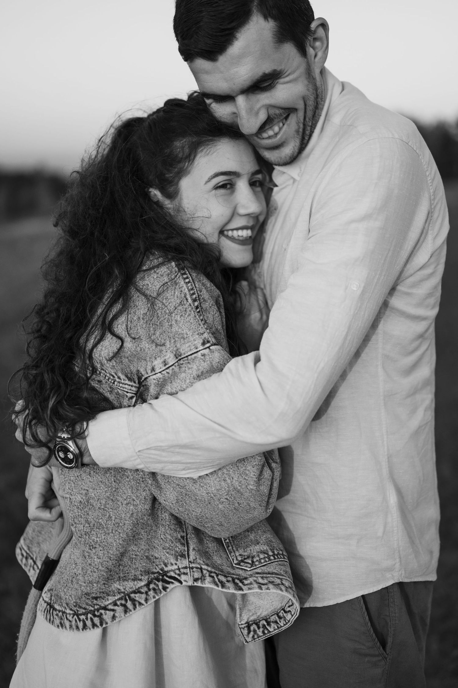 A romantic black and white photo series showing a couple embracing and laughing together outdoors.