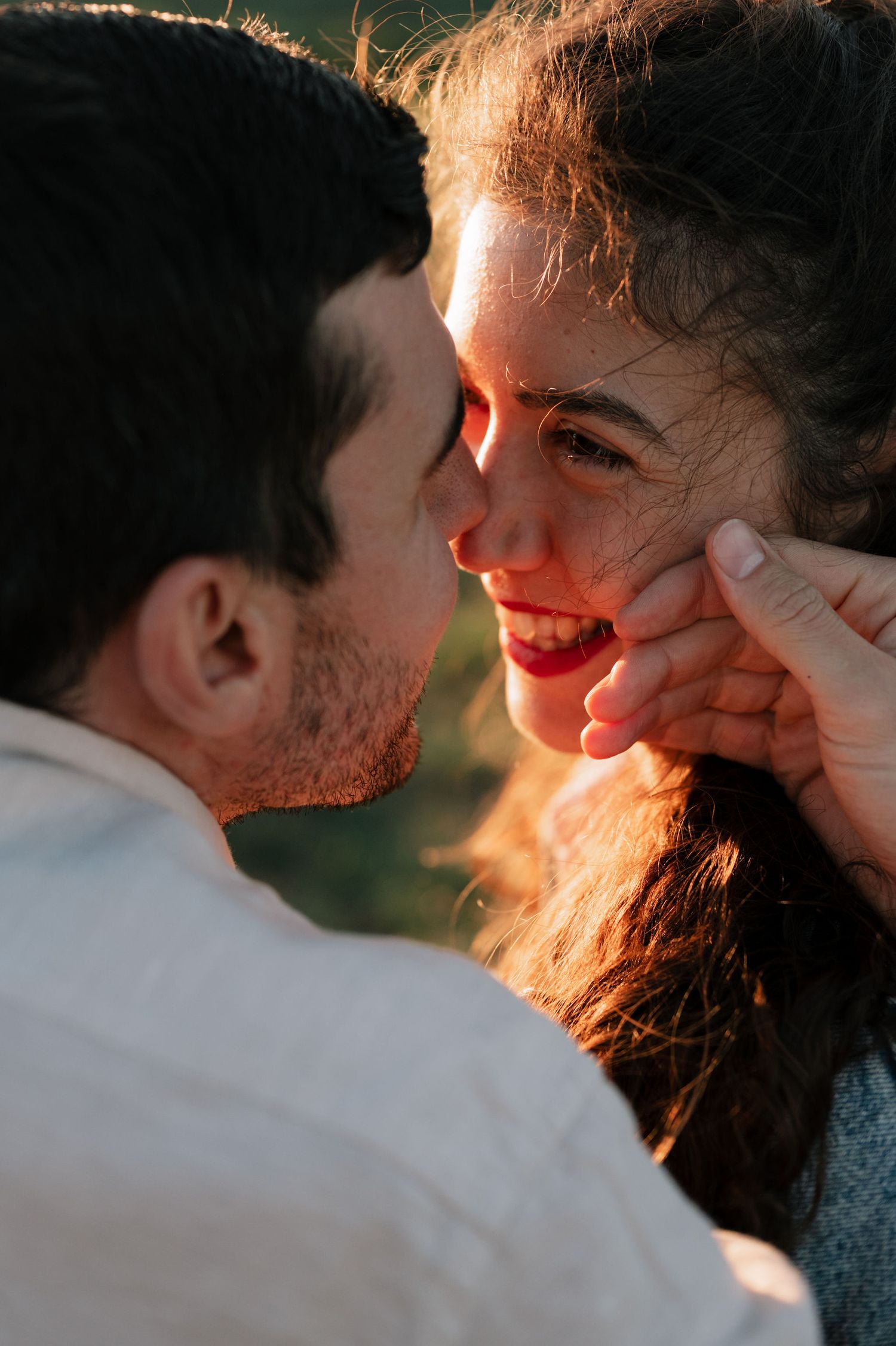 A romantic couple shares an intimate moment at sunset with golden light illuminating their faces.