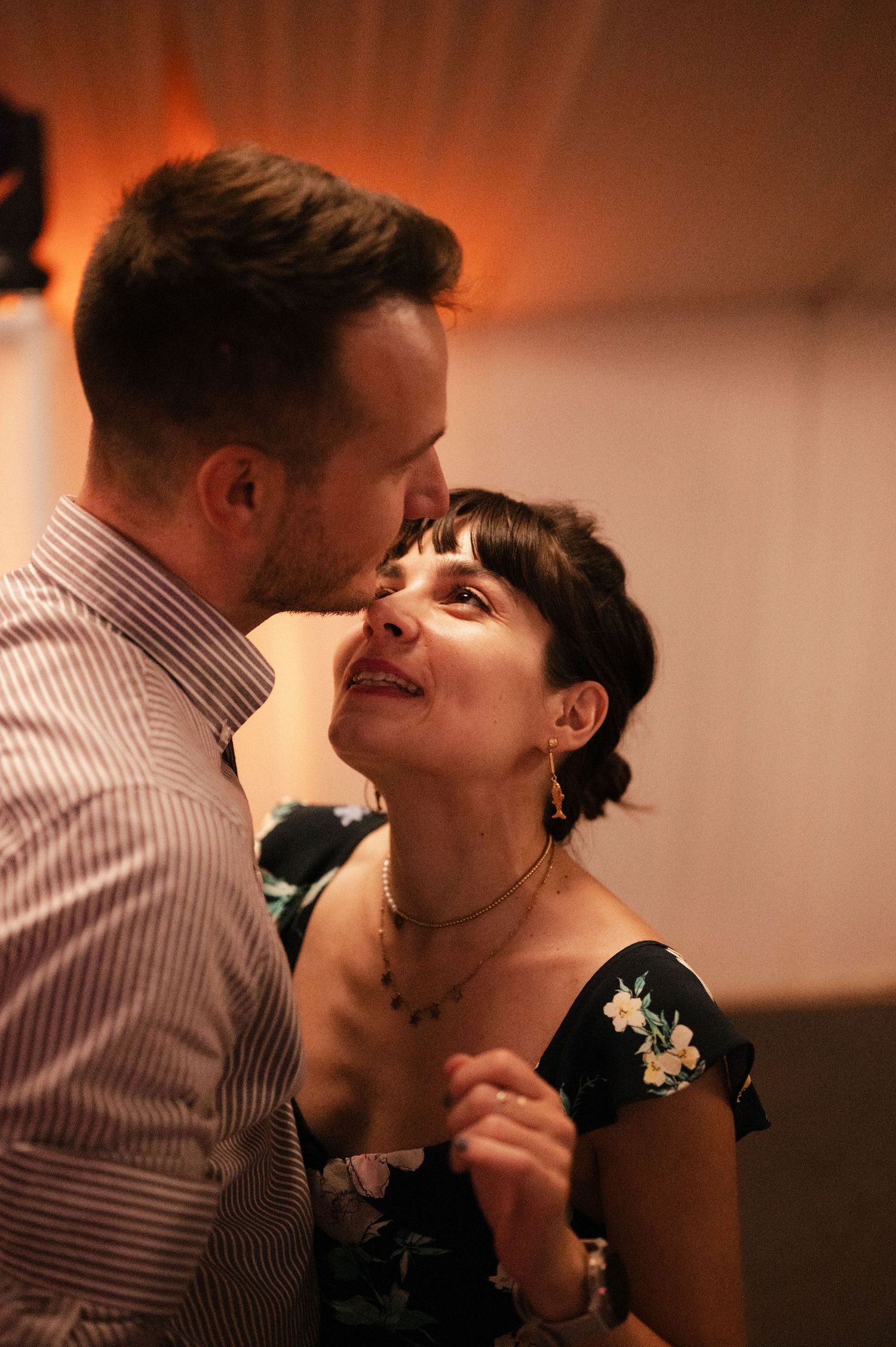A romantic couple shares an intimate moment in warm lighting while wearing striped clothing.