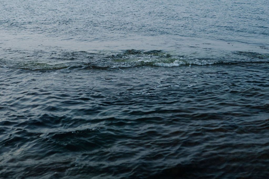 Aerial view of dark blue ocean waves rippling across the water surface on a cloudy day.