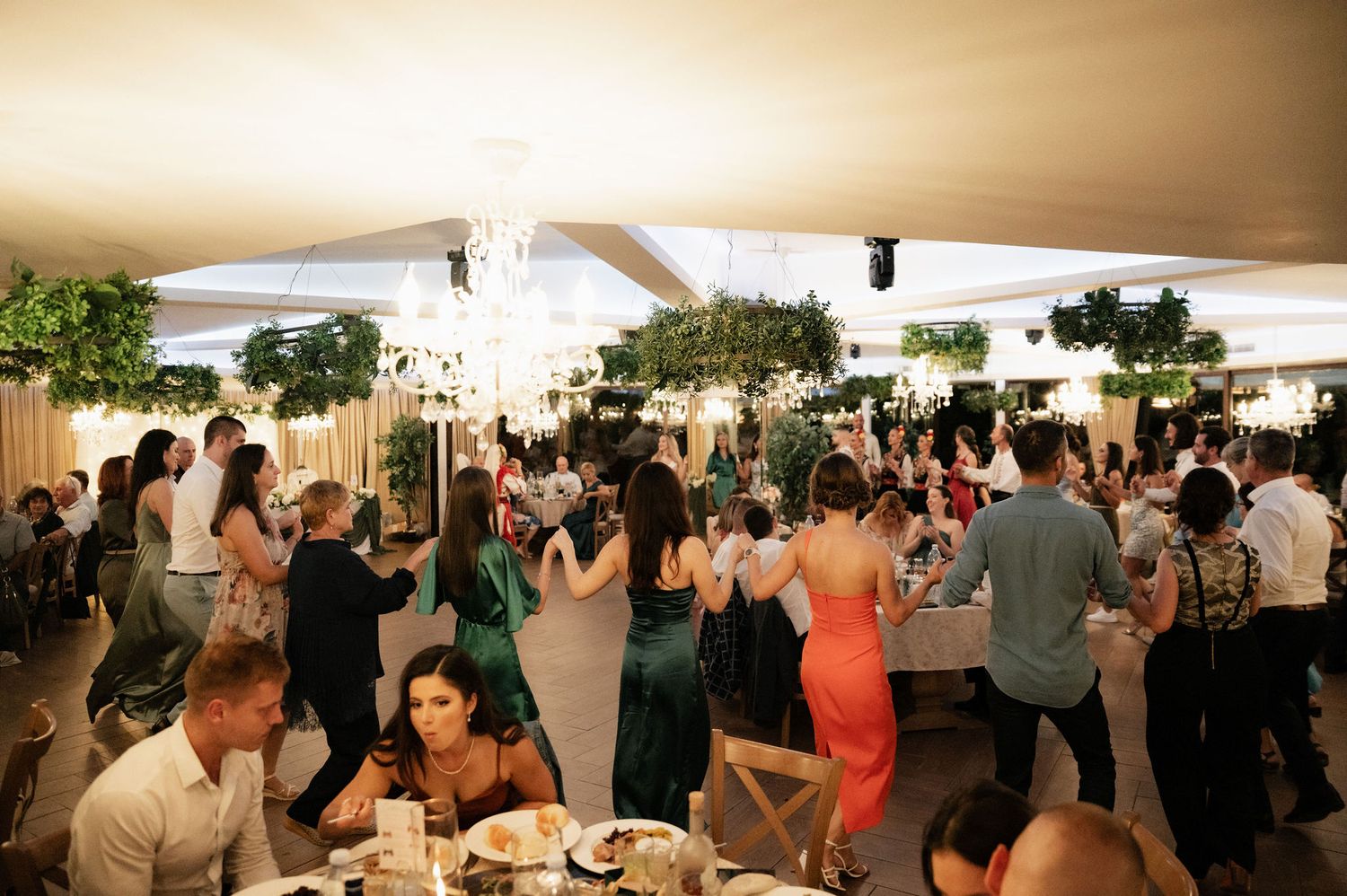 A panoramic view of a crowded indoor event space with people mingling under white tent-like structures.