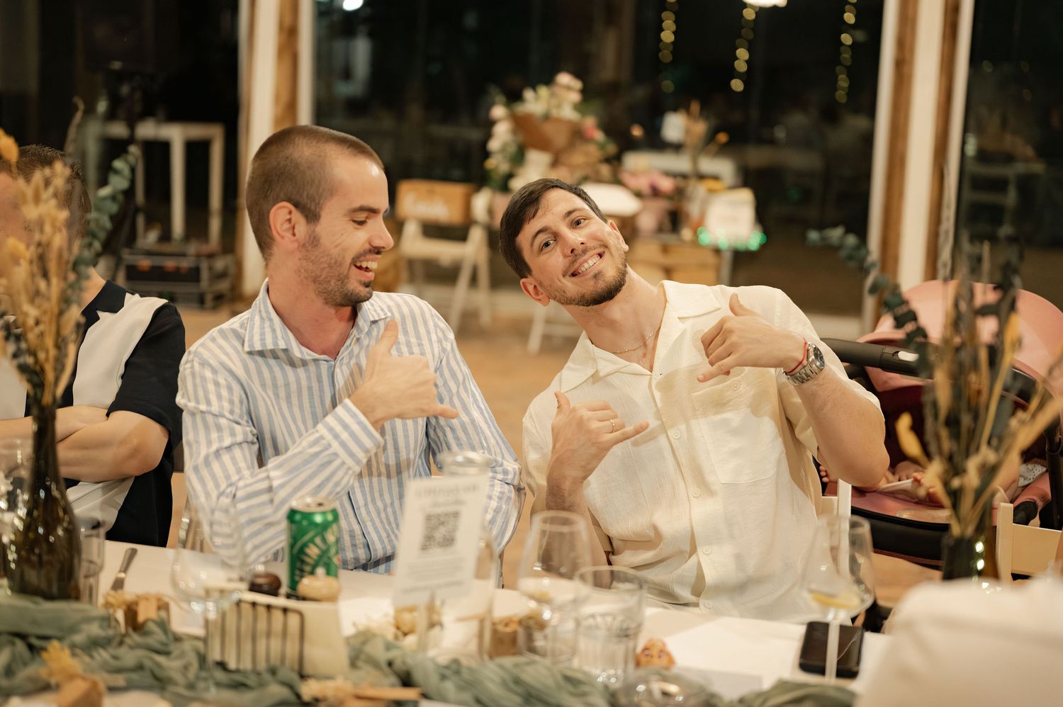 Wedding guests share laughter and conversation during an outdoor evening reception dinner at an elegant venue.