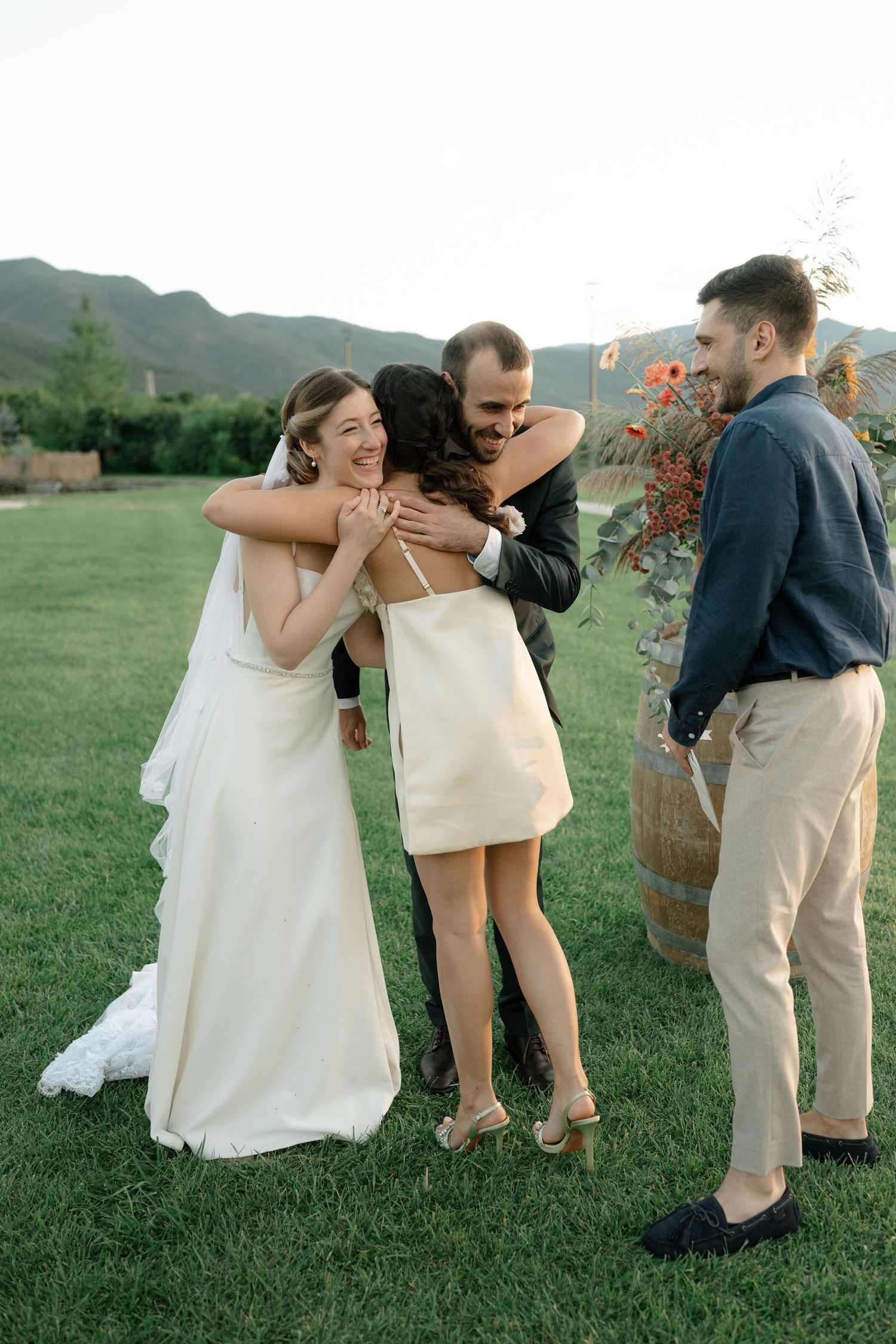 A joyful outdoor celebration on a grassy lawn with mountains in the background during a wedding event.