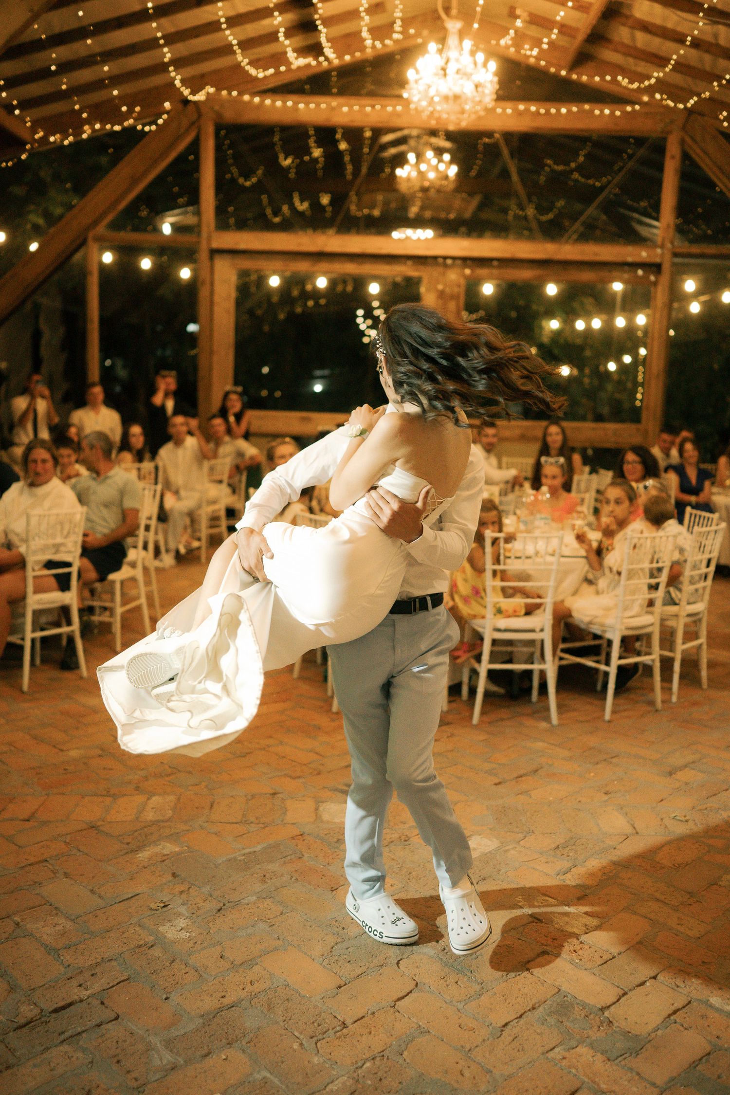 A dance performance showing athletic moves on a stone floor under twinkling lights at an indoor-outdoor venue.