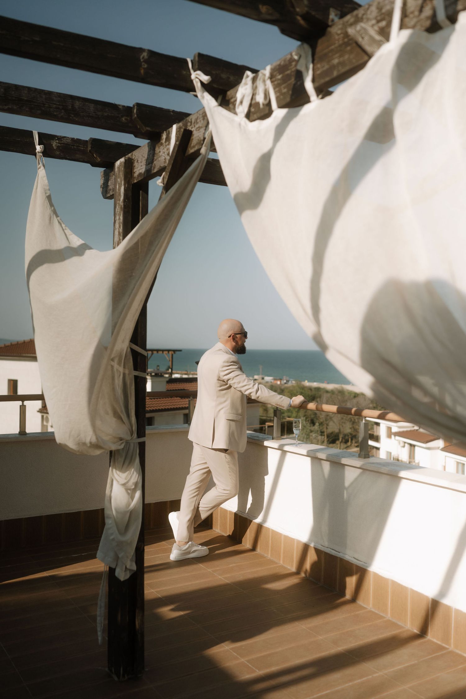Person hanging white sheets to dry on wooden beams in a sunlit room with wooden floors.