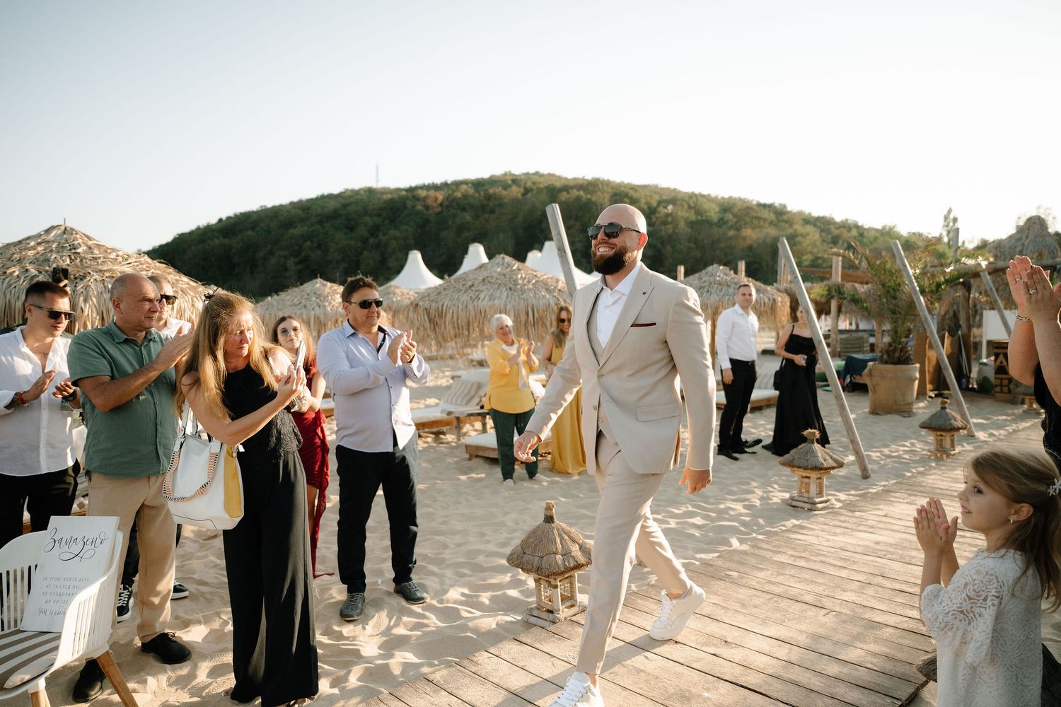 Wedding guests dance and celebrate during a golden hour reception on an outdoor patio with mountain views in the background.