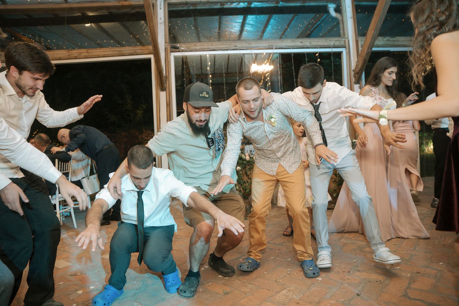 Wedding guests on a dance floor participate in a fun group dance activity at a reception celebration.