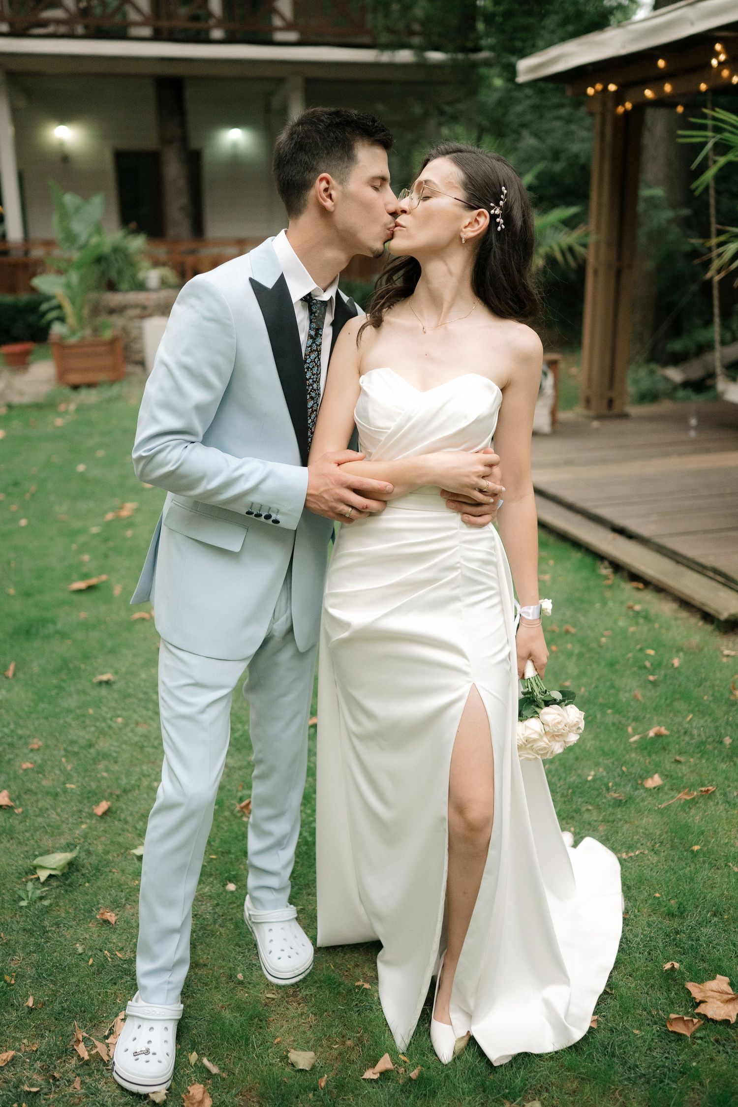Romantic wedding couple in white attire sharing intimate moments in a garden setting.