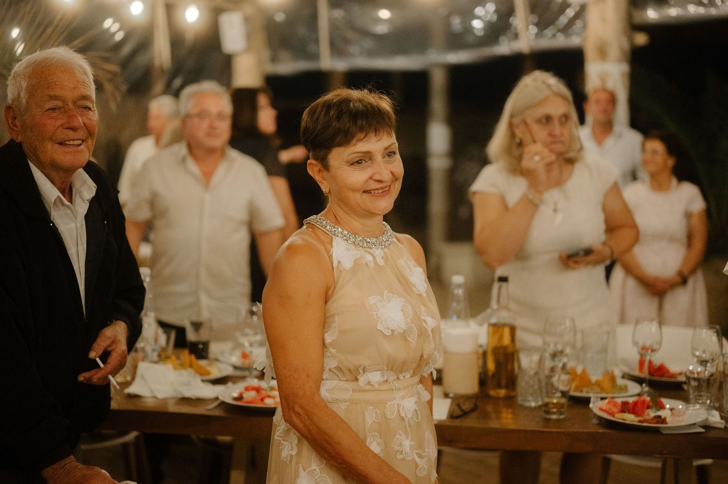 Guests enjoy an elegant evening celebration at a warmly lit indoor reception with drinks and dining tables.