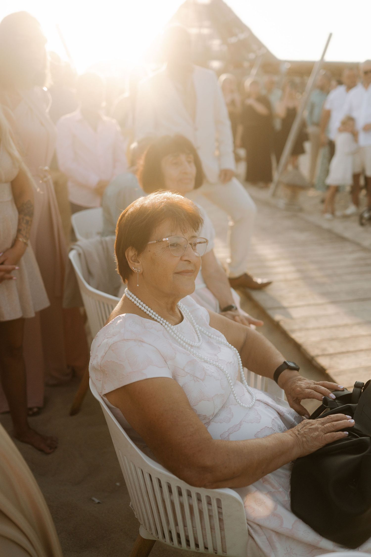 Woman in white shirt sits in outdoor chair during golden hour sunlight.