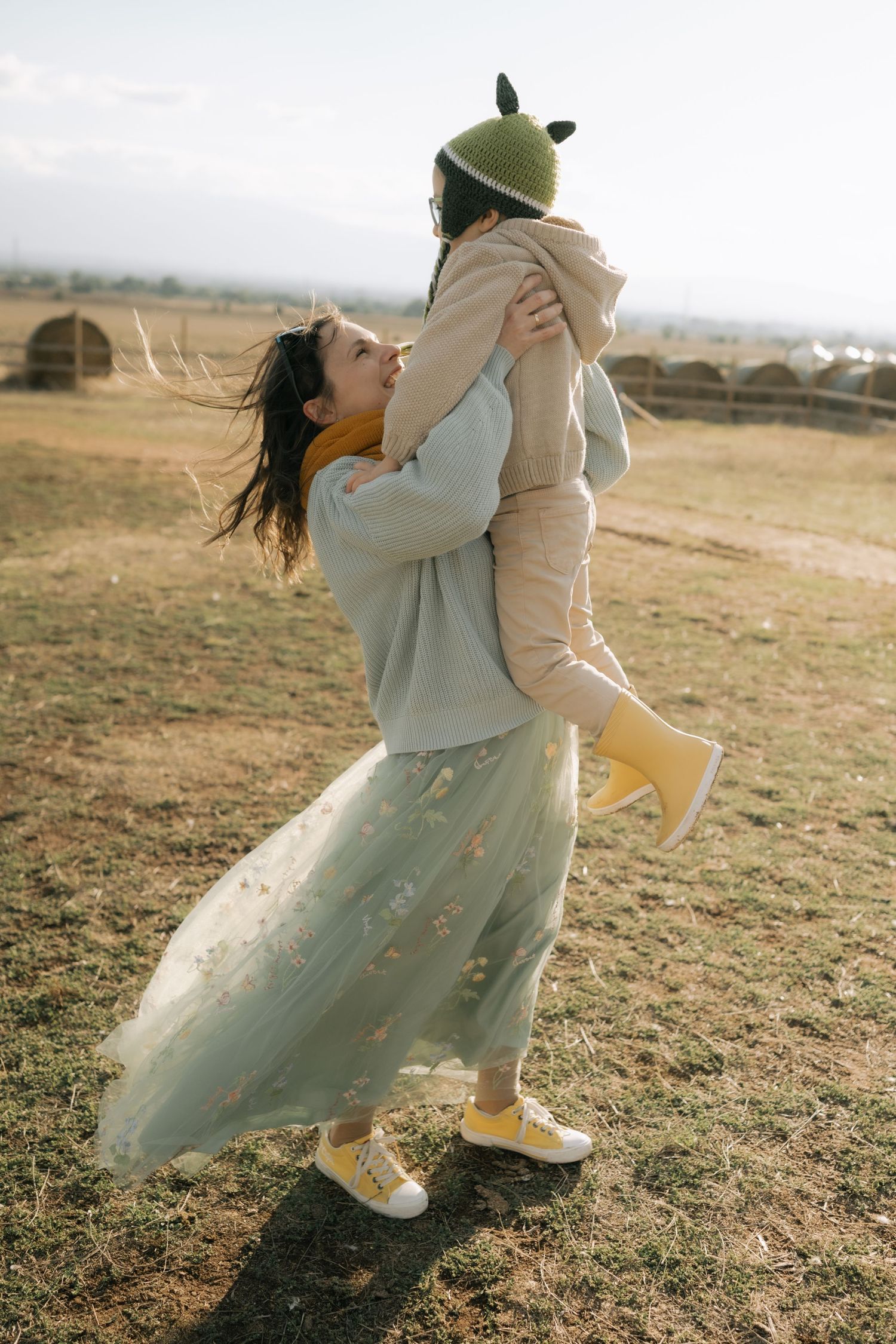 A person in a flowy white dress and boots dances and twirls in a golden field at sunset.