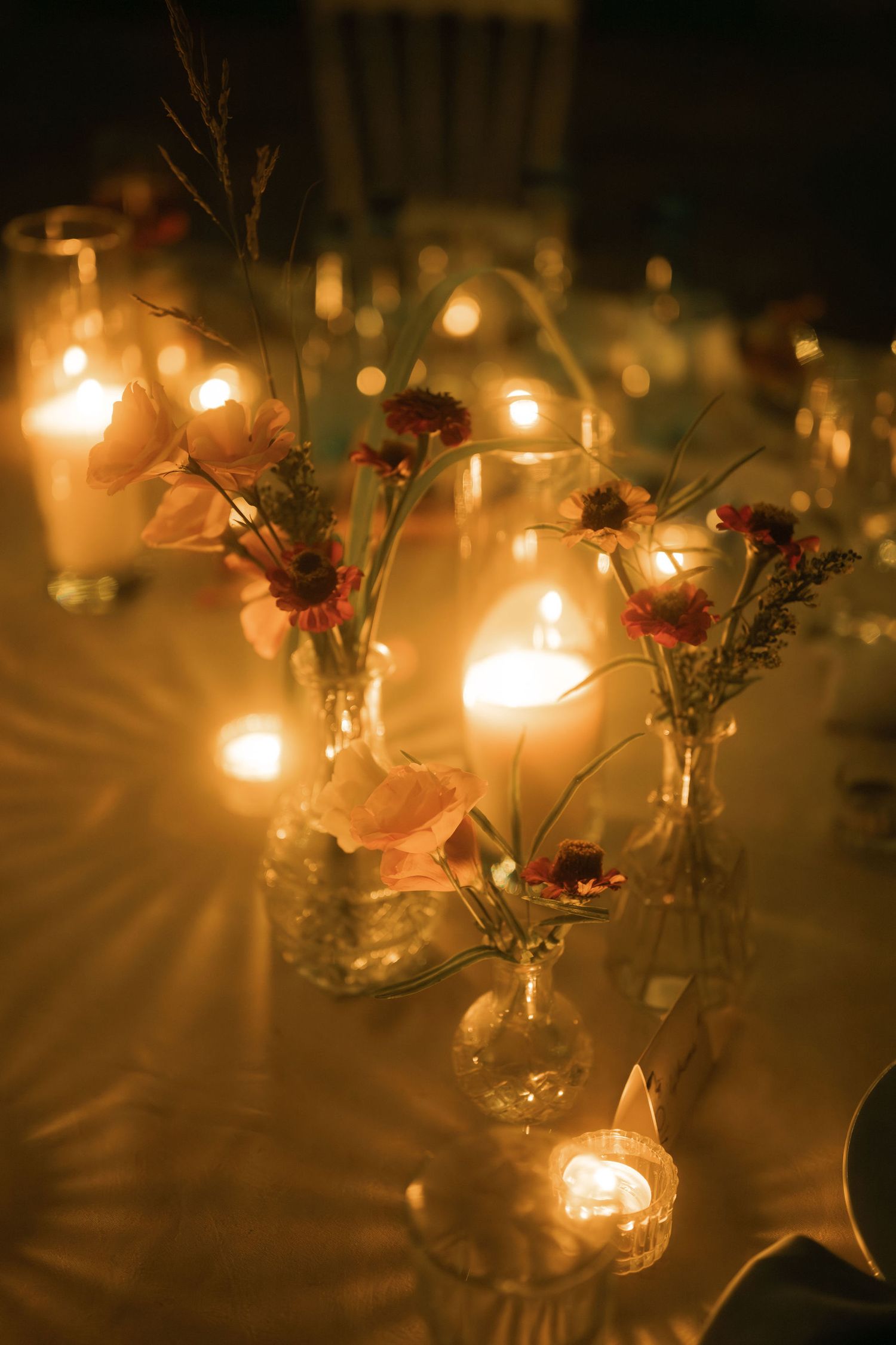 Glowing tea lights in glass holders decorated with delicate pink flowers create a romantic ambiance.