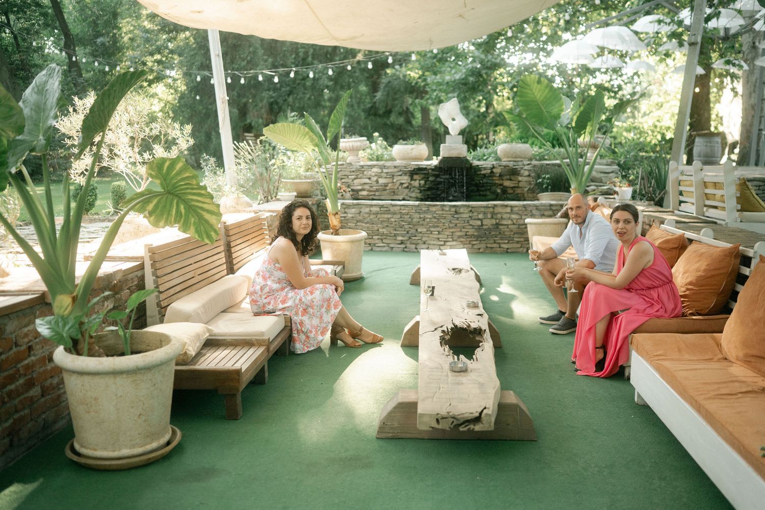 A cozy outdoor patio with wicker furniture, cushions, and hanging plants creates a relaxing garden atmosphere.