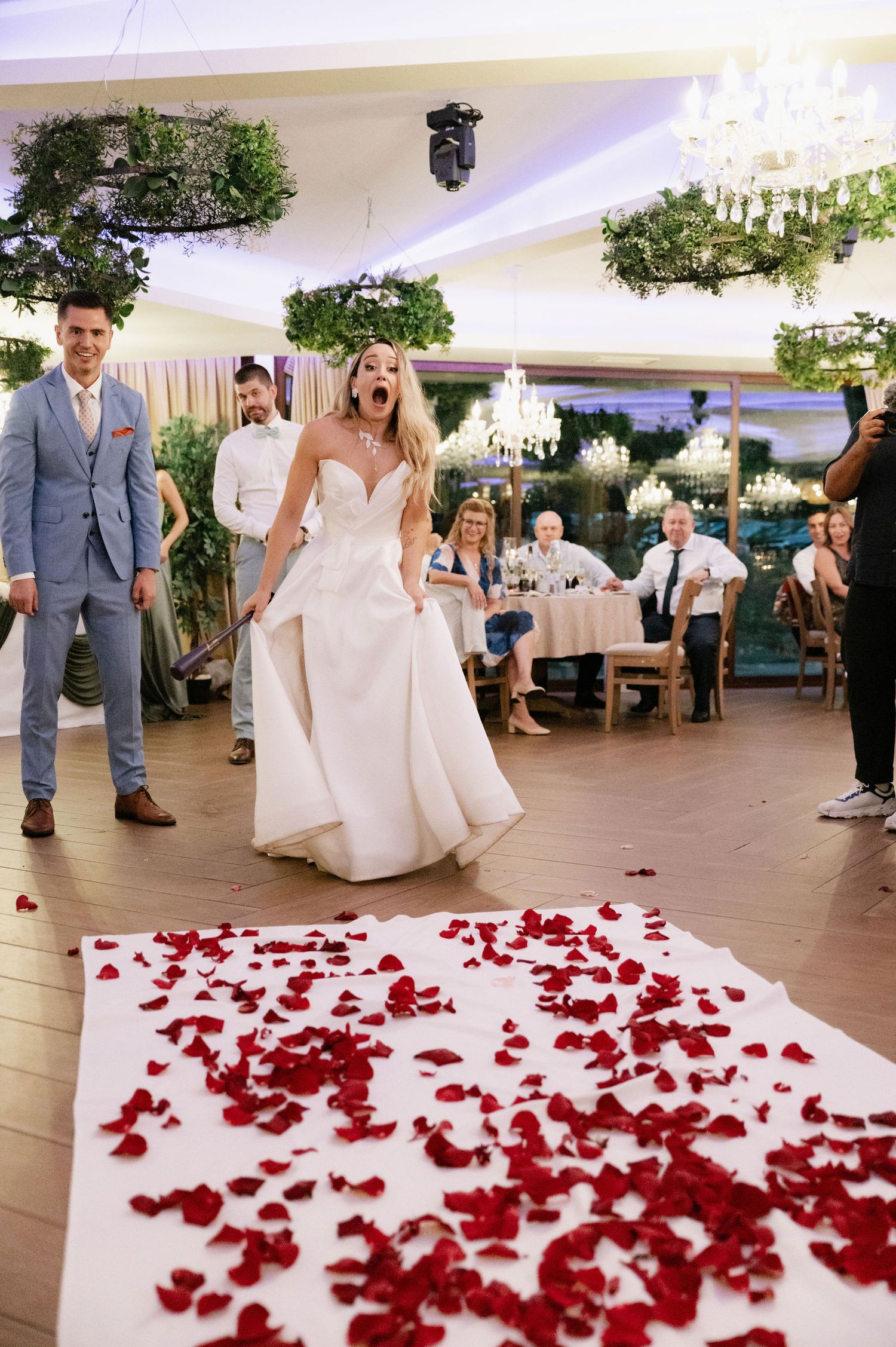 A sequence of wedding photos showing a couple playing with scattered red rose petals on a white dance floor.