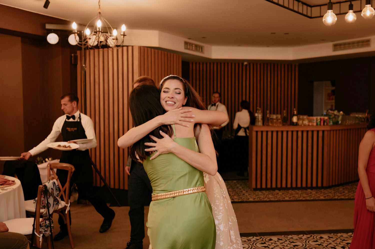 People dancing together in a ballroom with wood paneled walls and warm lighting.