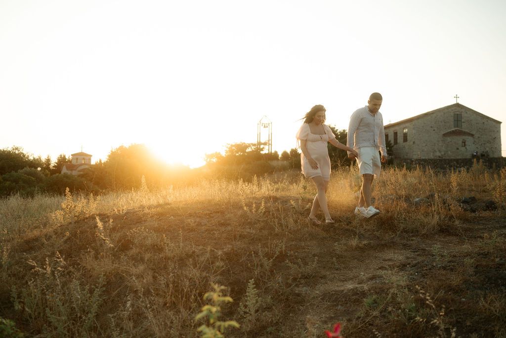 Silhouettes of people walking along a hillside path at golden sunset creating a dreamy atmospheric scene.
