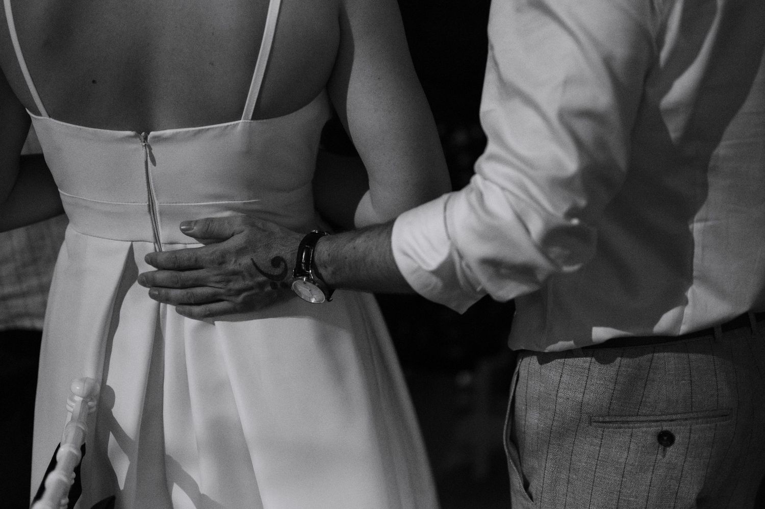 A row of wedding guests in formal attire stand together holding champagne glasses during a celebration.