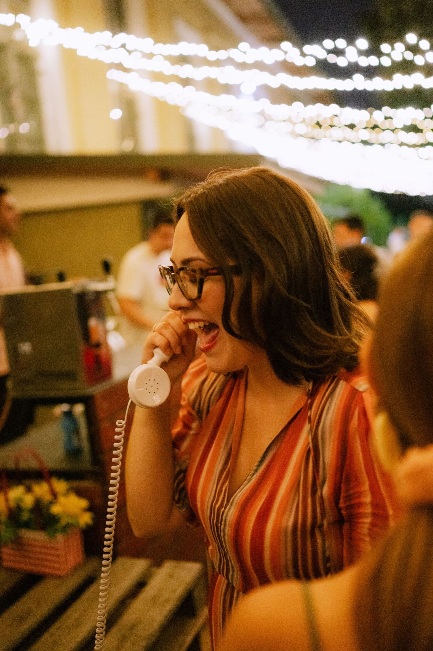 Four sequential photos show a person in glasses laughing joyfully under warm lighting at an indoor event.
