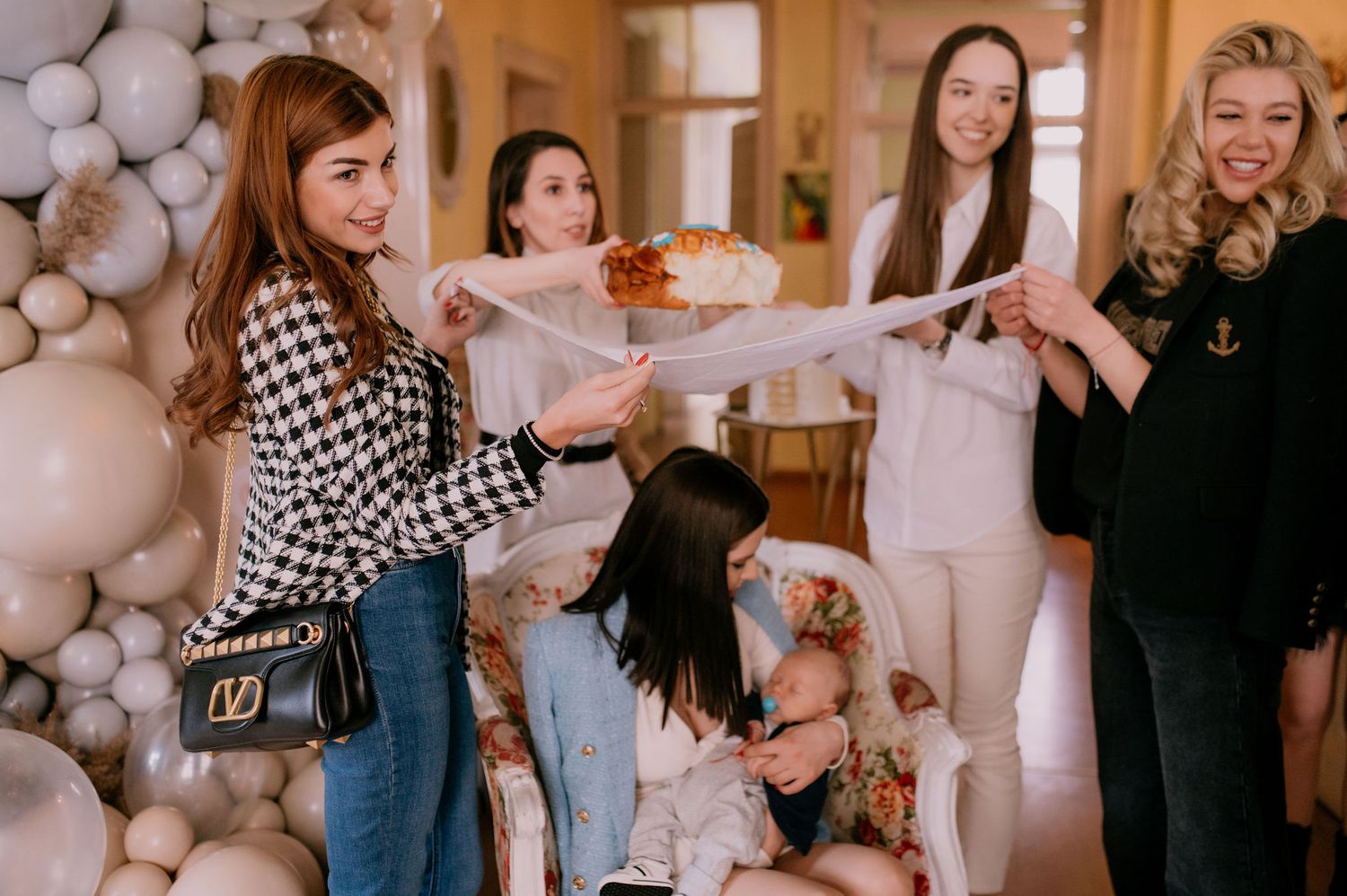 Friends gathered at an indoor celebration with balloon decorations and checkered patterns visible.