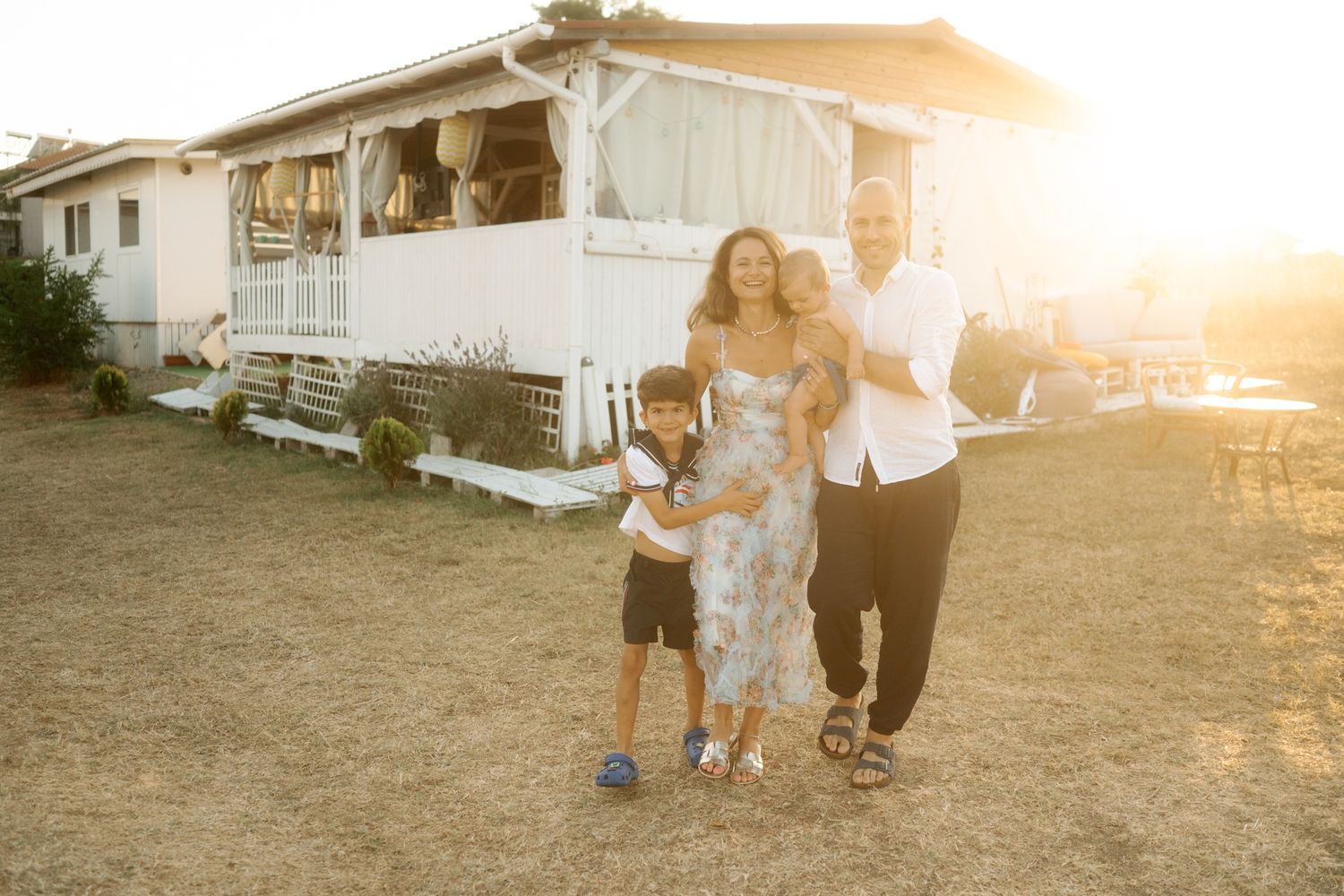 Group of people walking together at sunset with lens flare and mobile homes in the background.