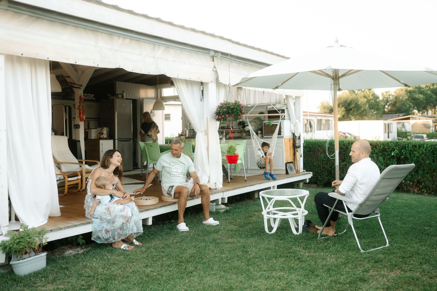 White chairs and tables arranged on a lawn for an outdoor wedding reception at sunset.